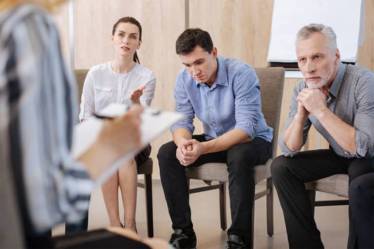 Adult people on chairs during intervention for substance abuse.