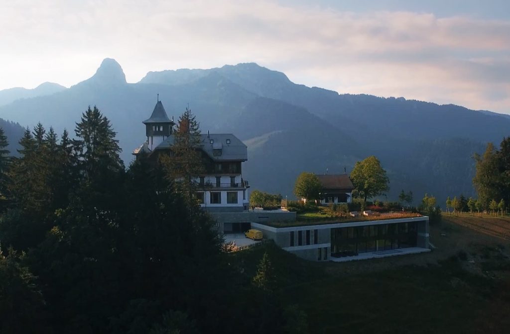 a building with trees and mountains in the background