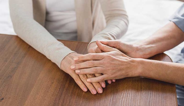 Supporting and helping someone with a cocaine addiction - holding hands across the table.