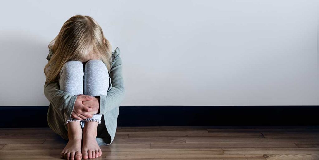 a girl sitting on the floor with her head in her hands